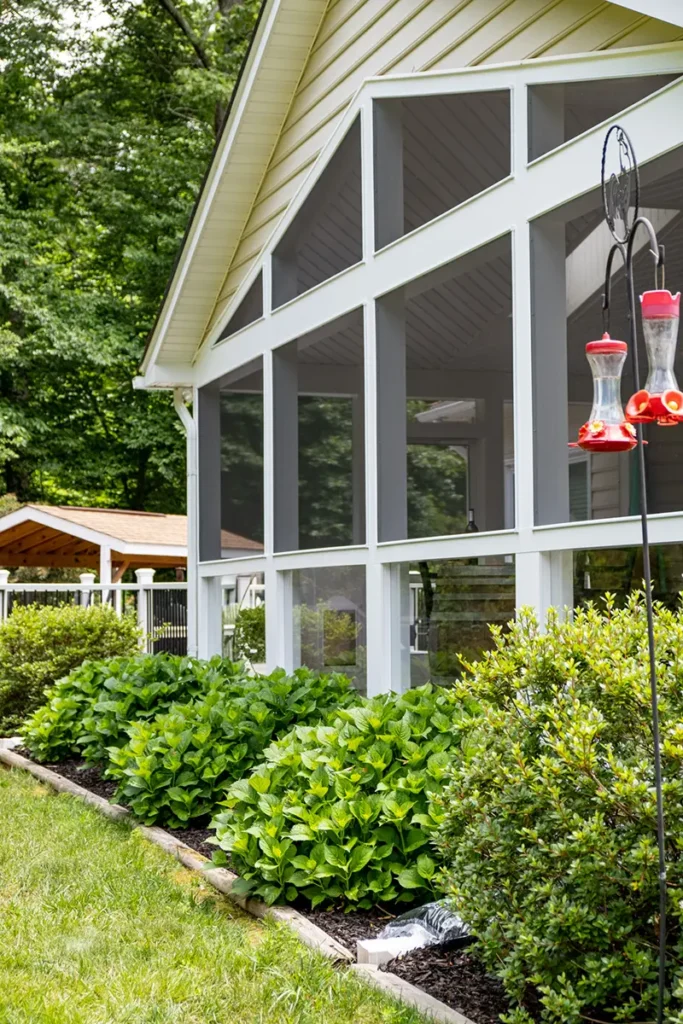 Screened porch with a tall gable end and large screen panels on a wooded lot