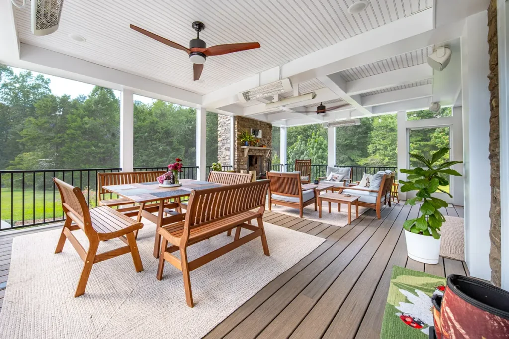 Covered porch with a beadboard ceiling, ceiling fans, stone fireplace and composite floor in Fredericksburg, VA