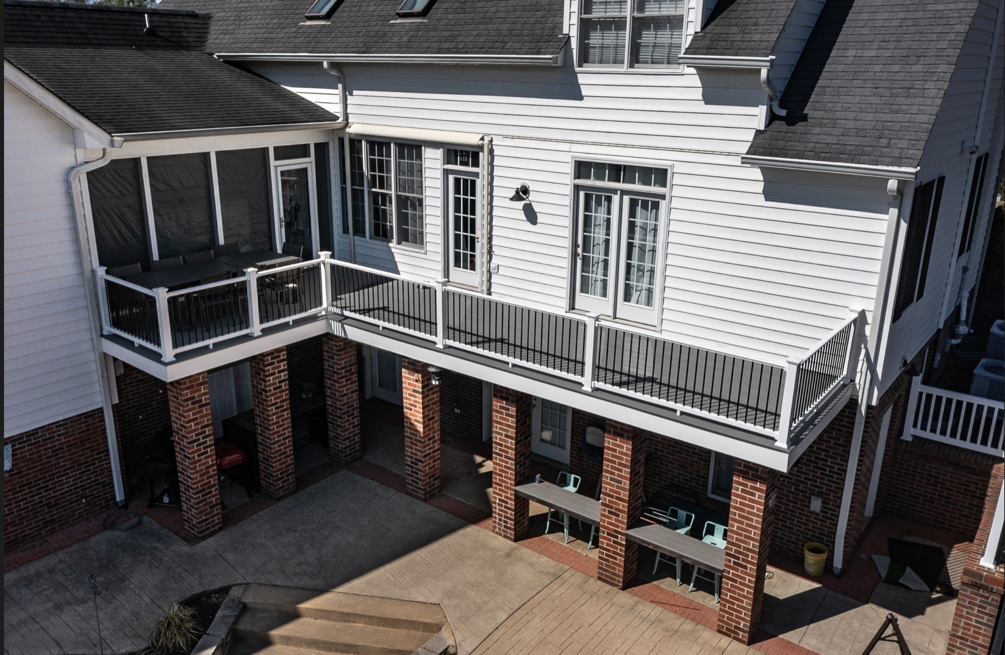 Screened porch above an open deck carried on finished brick piers rather than lattice skirting